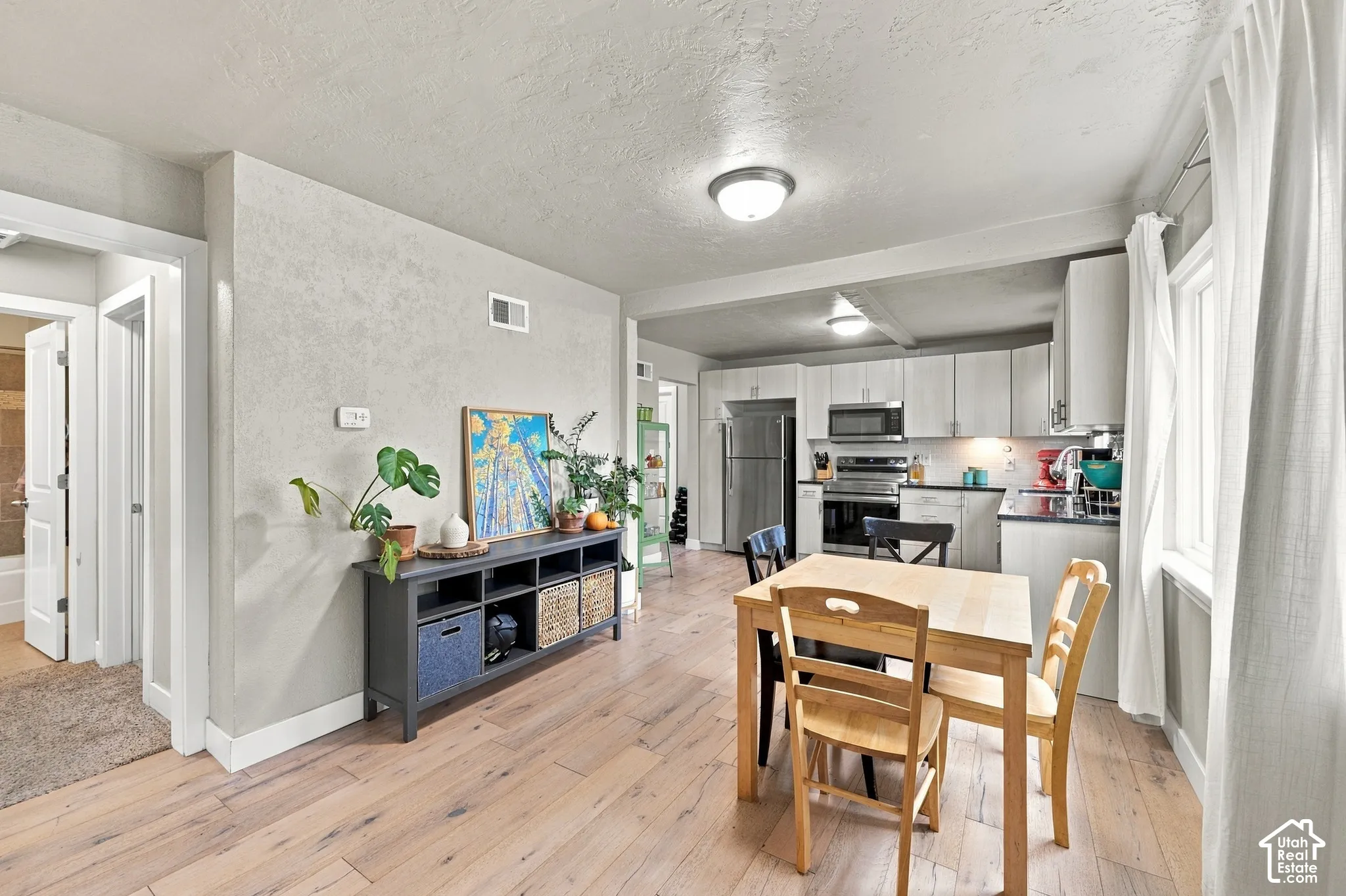 Kitchen featuring light-toned cabinetry, stainless steel appliances, wood-finish flooring, and recessed ceiling lighting