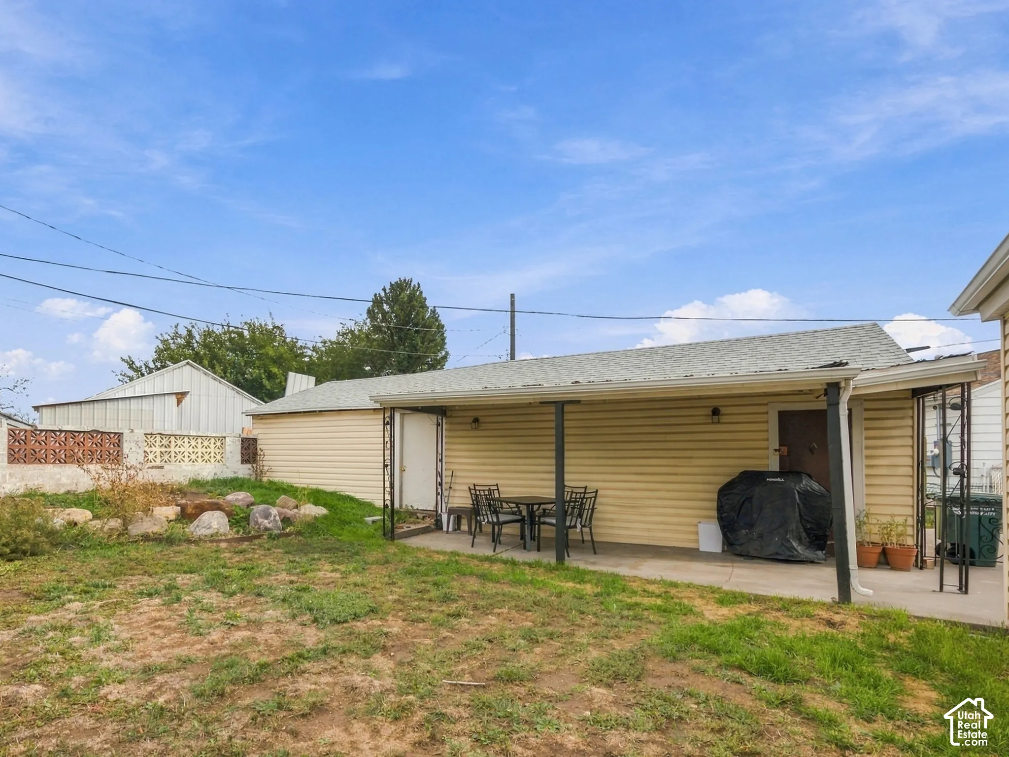 Backyard featuring a covered concrete patio, garage with siding and masonry wall