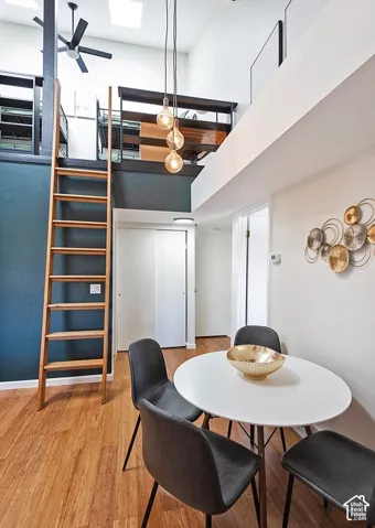 Vaulted ceilings featuring pendant lighting, integrated loft level with a fixed wooden ladder, and wood-finish flooring