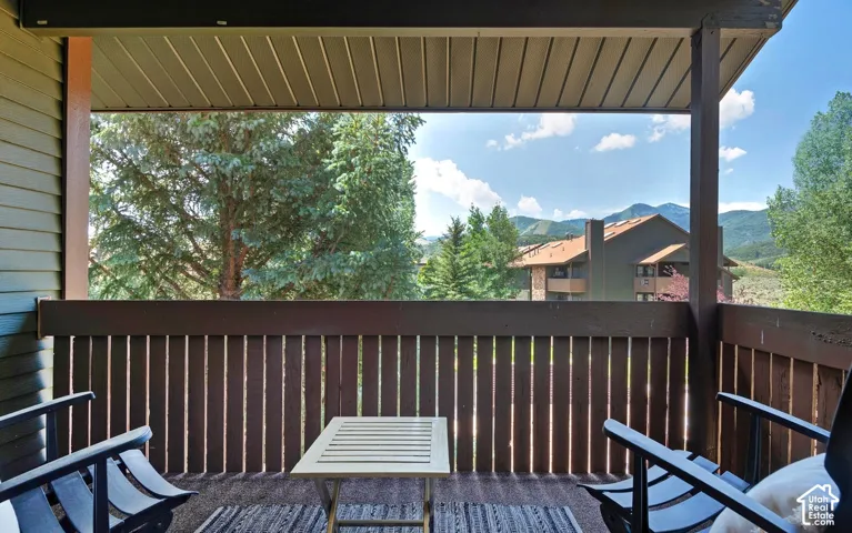 Covered balcony featuring vertical wood slat railings, green siding, and mountain scenery