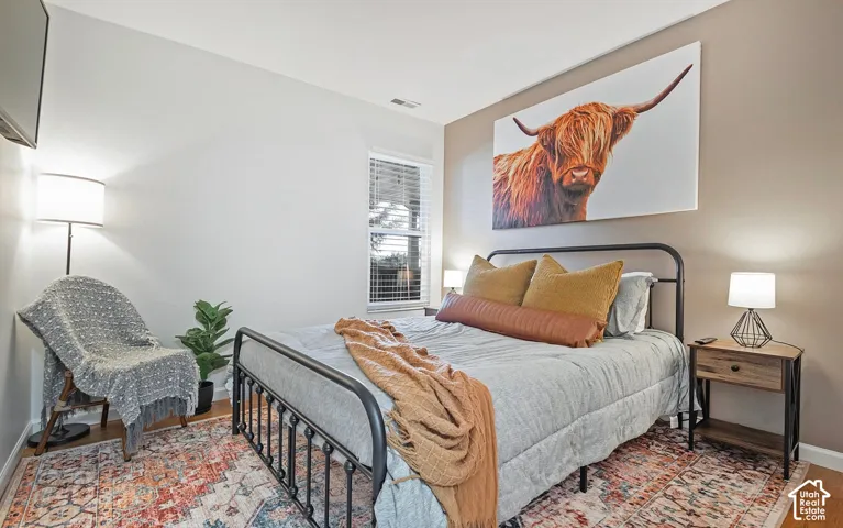 Neutral-toned walls featuring a single accent wall, window with horizontal blinds, and wood-finish flooring