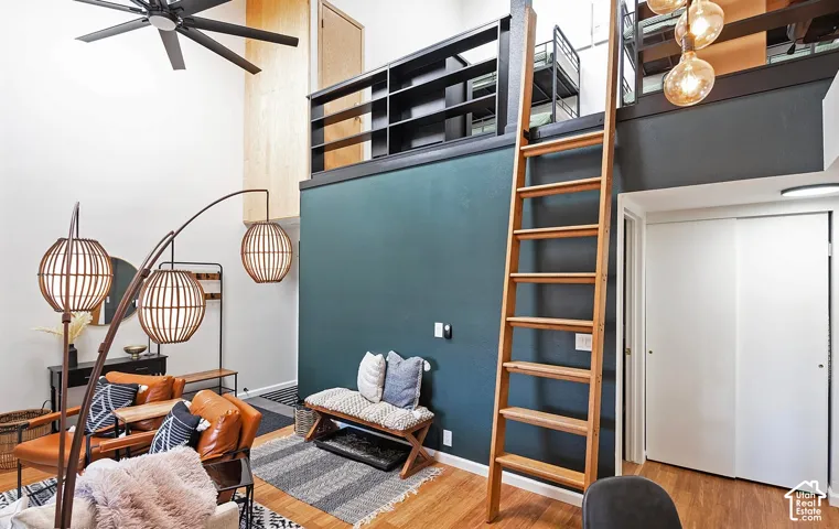 Vaulted ceilings, wood-finish flooring, built-in wooden ladder, elevated mezzanine with black railing, and dual-panel sliding closet doors