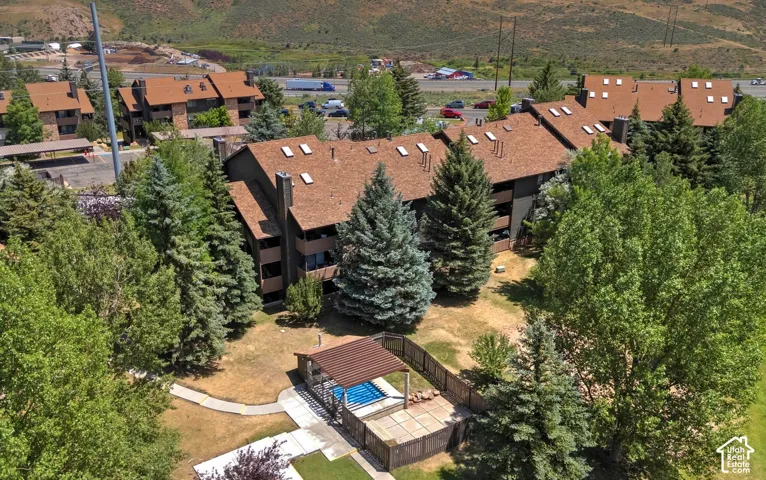 Multi-story residential complex featuring shingled roofing with integrated skylights, covered exterior balconies, and a fenced common area with a pergola-shaded pool
