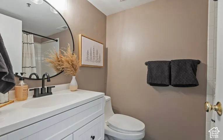 White vanity cabinet with a solid surface countertop, integrated sink, matte black widespread faucet, and oval wall mirror with a black frame