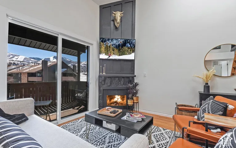 Full-height board-and-batten fireplace surround with a textured masonry hearth and sliding glass door access to a balcony with a mountain backdrop