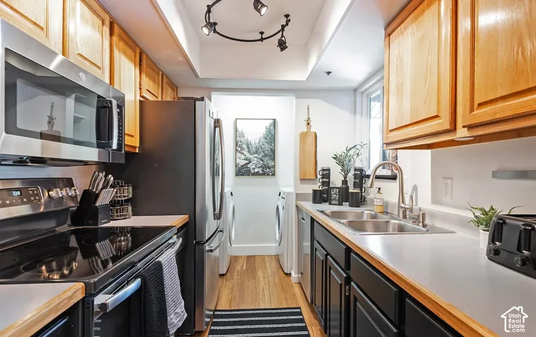 Kitchen featuring natural wood cabinetry, solid-surface countertops, stainless steel appliances, recessed ceiling lighting, and wood-finish flooring