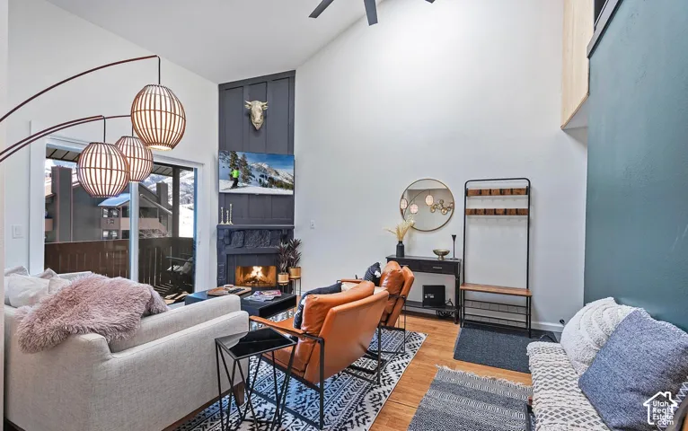 Vaulted ceilings, wood-finish flooring, floor-to-ceiling fireplace surround, and sliding glass doors