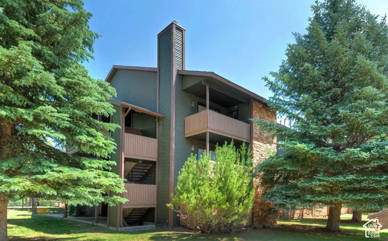 Multi-level exterior featuring horizontal lap siding, vertical stone veneer accents, integrated chimney, and dual-level balconies
