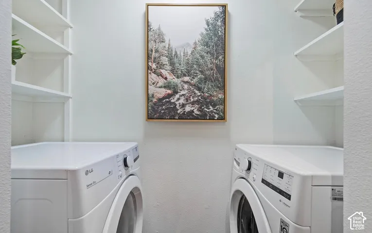Dedicated laundry area featuring white front-load appliances and tiered built-in shelving