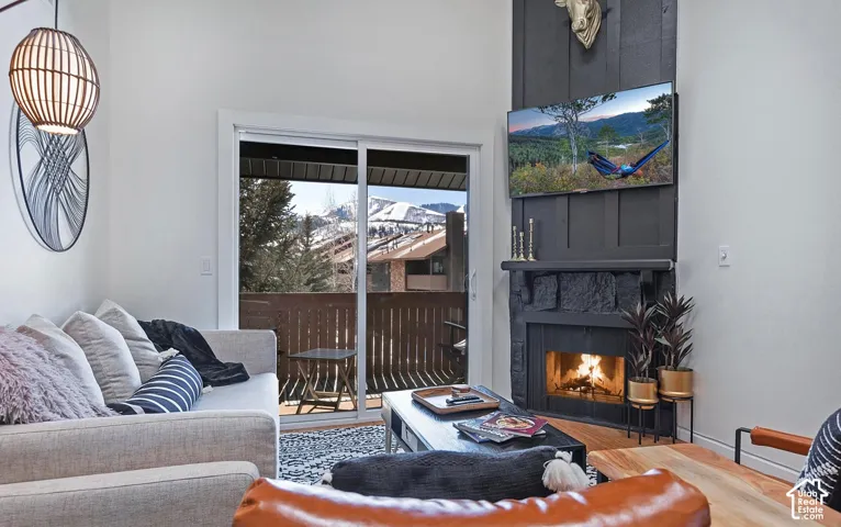 Living area featuring a floor-to-ceiling fireplace with stone hearth and vertical board accent, sliding glass doors, and mountain backdrop