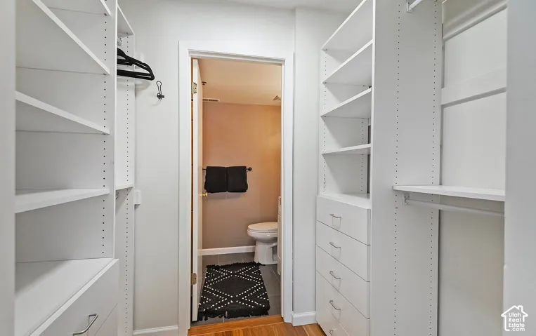 Walk-in closet featuring white built-in shelving, integrated dresser drawers, and hanging rods
