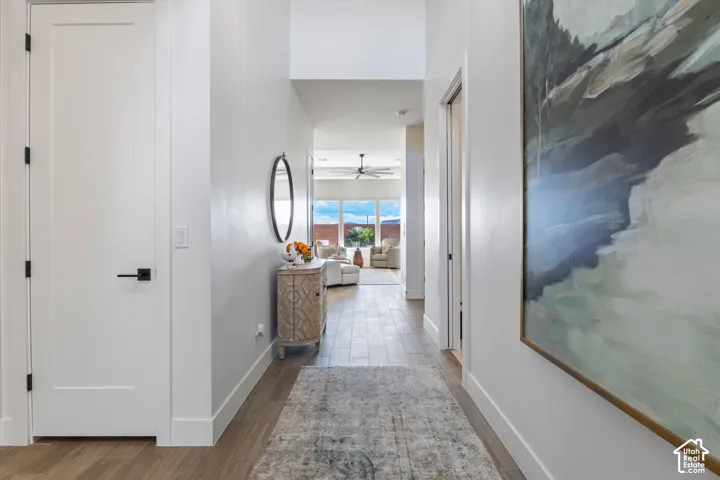 Entryway featuring high ceilings, wood-finish flooring, solid-core doors with matte black hardware, and crisp neutral wall paint