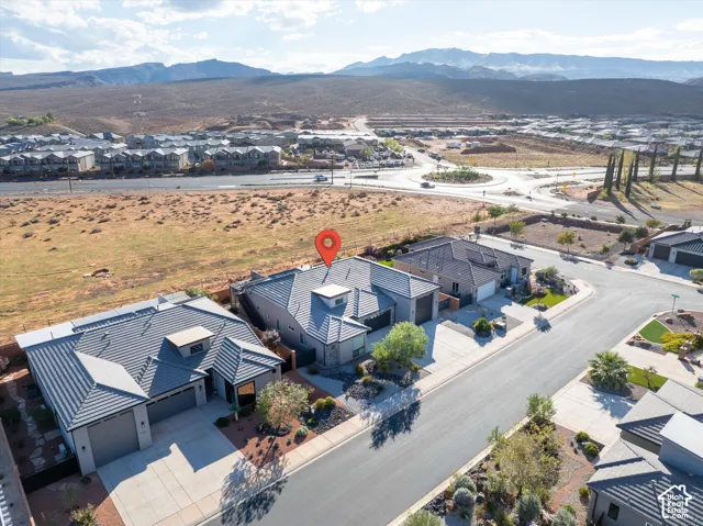 Single-story residence featuring a tile roof, multi-car garage, concrete driveway, and xeriscaped front grounds set against a mountain backdrop