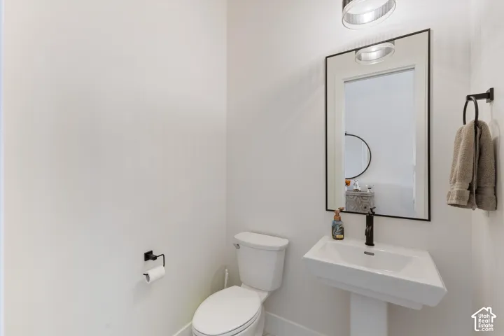 Modern powder room featuring a geometric pedestal sink, rectangular mirror with a slim black frame, matte black hardware, and contemporary glass globe lighting