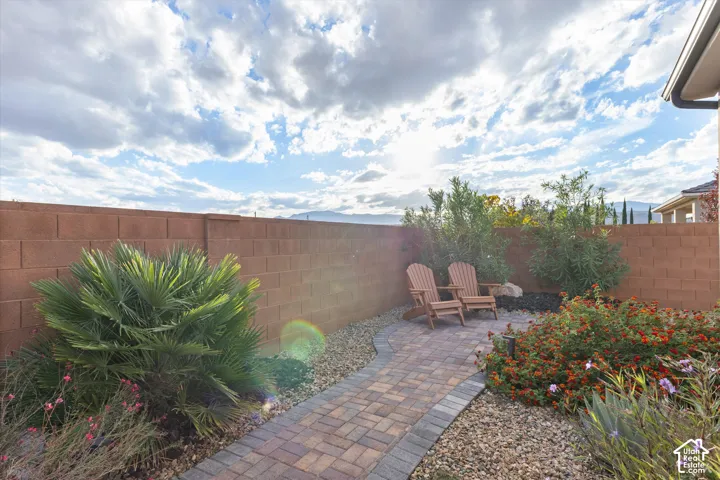 Private backyard featuring a paver stone patio, decorative gravel landscaping, mature shrubbery, and a masonry perimeter wall