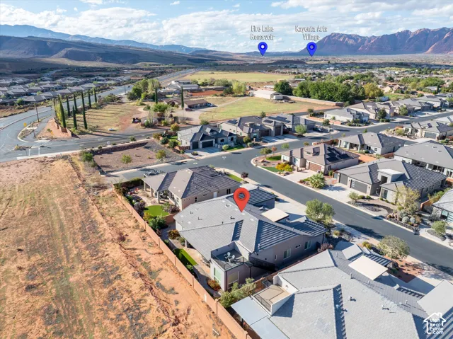 Aerial perspective of a residential property featuring a tile roof, an enclosed backyard with artificial turf, and a second-level balcony