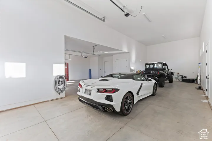 Expansive multi-bay garage featuring high ceilings, neutral painted walls, concrete flooring, and interior wall-mounted hose storage