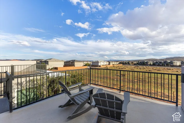 Elevated terrace featuring a durable, textured surface and black metal railings, overlooking a desert landscape with mountain silhouettes