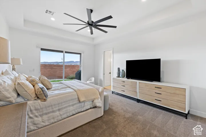Tray ceiling with a multi-blade matte black ceiling fan, recessed lighting, and large sliding glass door with exterior mountain scenery