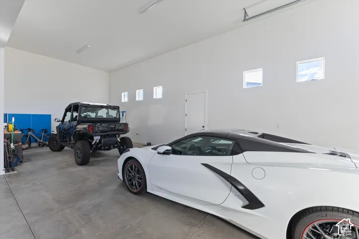 High-ceiling garage with concrete flooring, finished drywall, and multiple clerestory windows