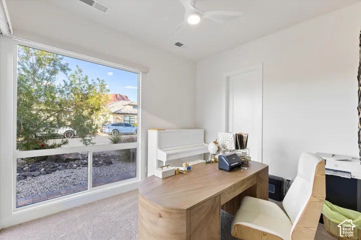 Large window with white frame, ceiling fan with integrated lighting, and carpeted flooring