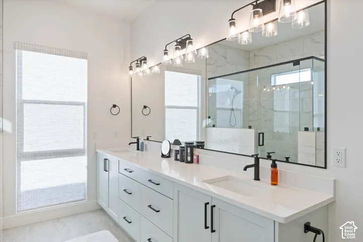 Double vanity featuring white cabinetry, quartz countertops, undermount sinks, matte black hardware, and an expansive wall mirror