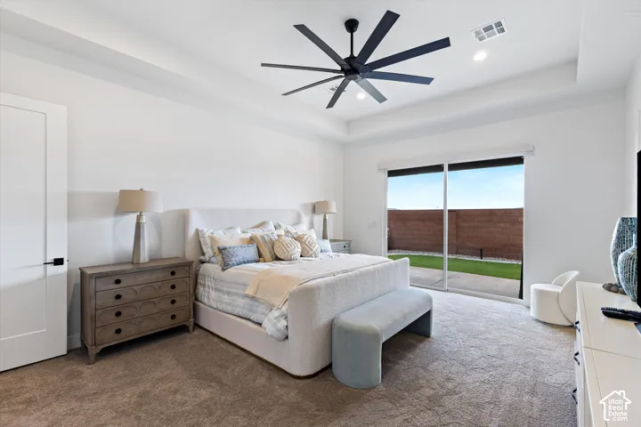 Tray ceiling with a multi-blade matte black ceiling fan, recessed lighting, and large sliding glass doors opening to a concrete patio
