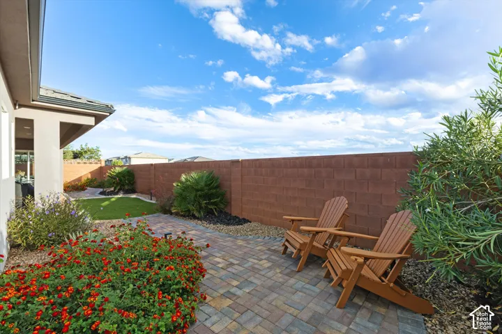 Backyard featuring a paver patio, masonry privacy wall, artificial turf, and established landscaping