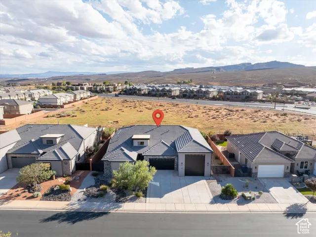 Single-story residence featuring a tile roof, stone masonry accents, a multi-car garage, and concrete driveway