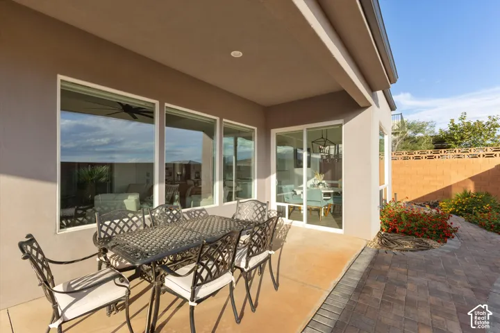 Covered concrete patio featuring large picture windows, a sliding glass door, and paver hardscaping