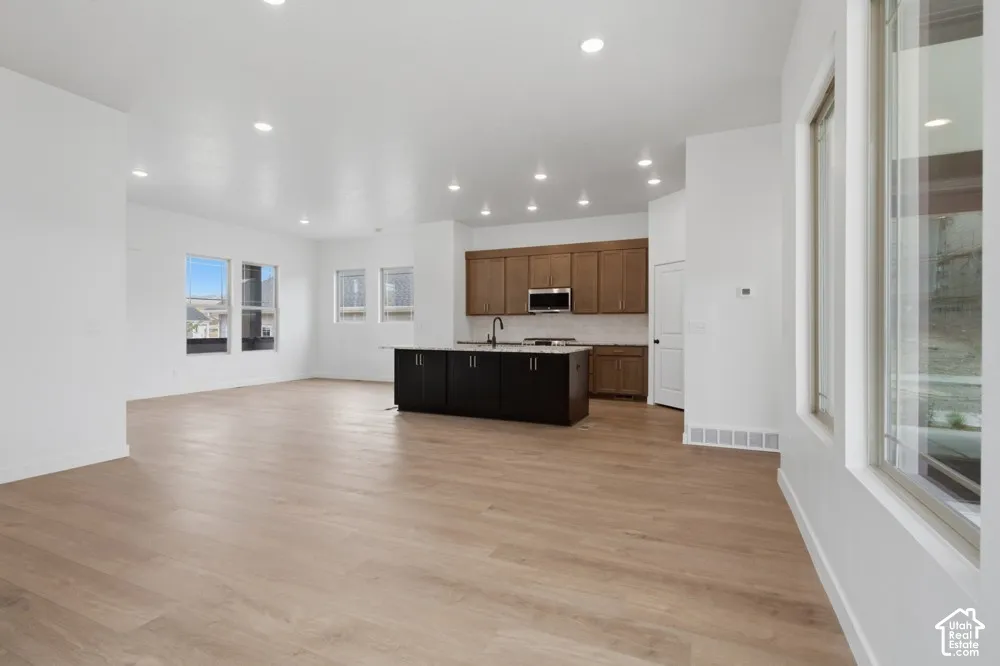Open-concept space featuring wood-finish flooring, recessed lighting, a contrasting kitchen island, wood-finish cabinetry, and built-in appliances