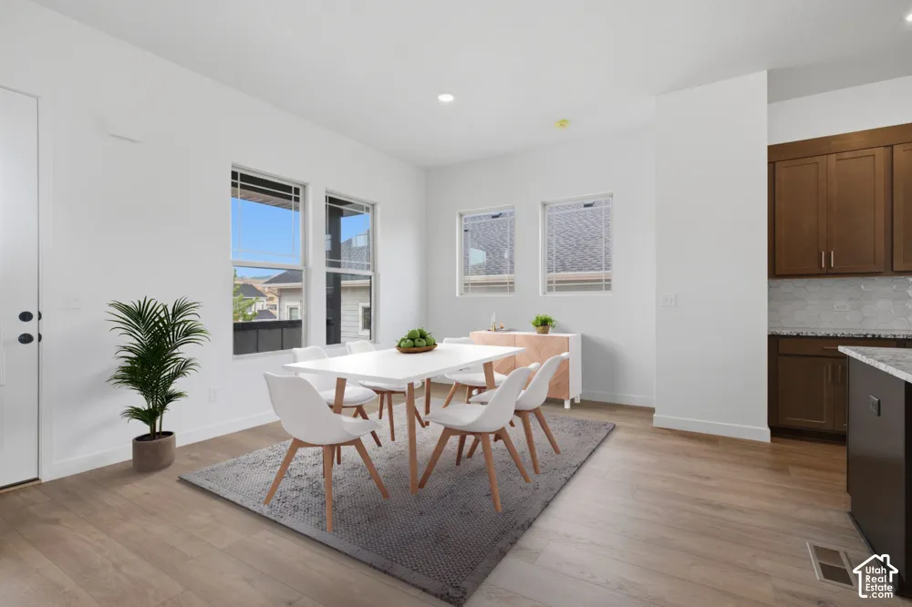 Open-concept area featuring wood-finish flooring, recessed lighting, double-pane windows, and shaker-style cabinetry with stone countertops