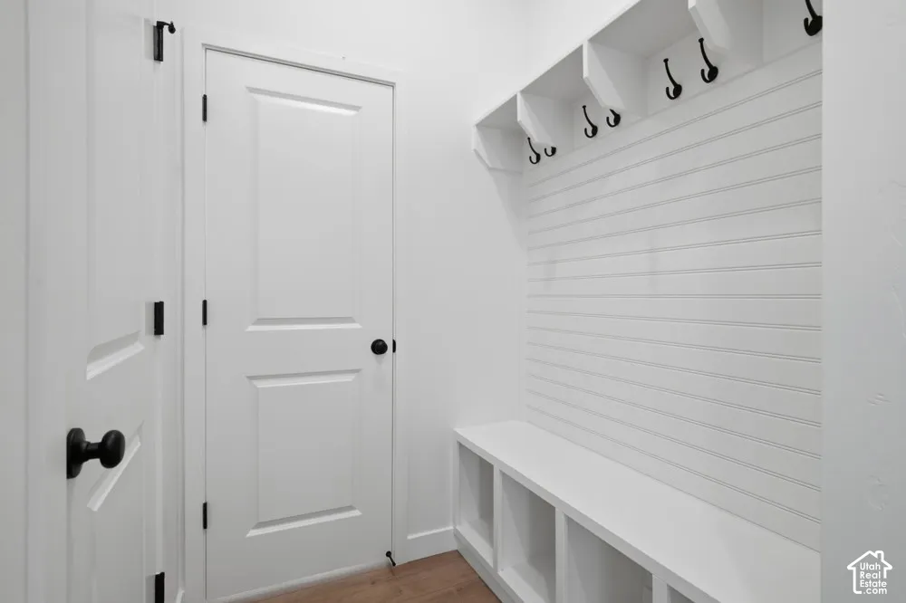 Built-in storage bench with lower cubbies, horizontal wall paneling, and upper shelving with integrated hooks featuring matte black hardware