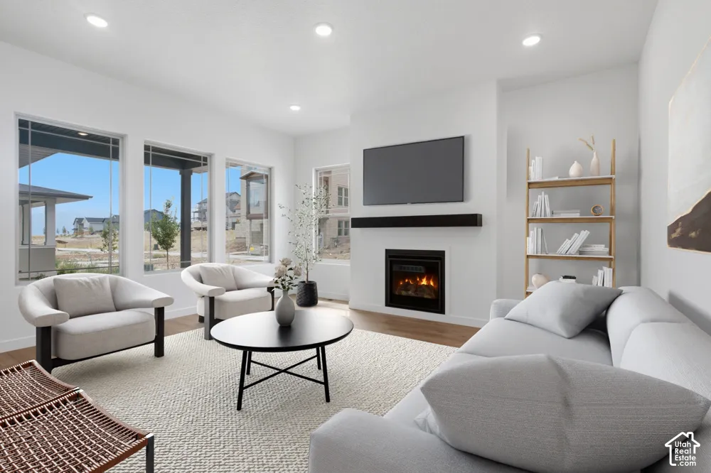 Living area featuring a fireplace with a linear mantel, multiple windows, recessed lighting, and wood-finish flooring