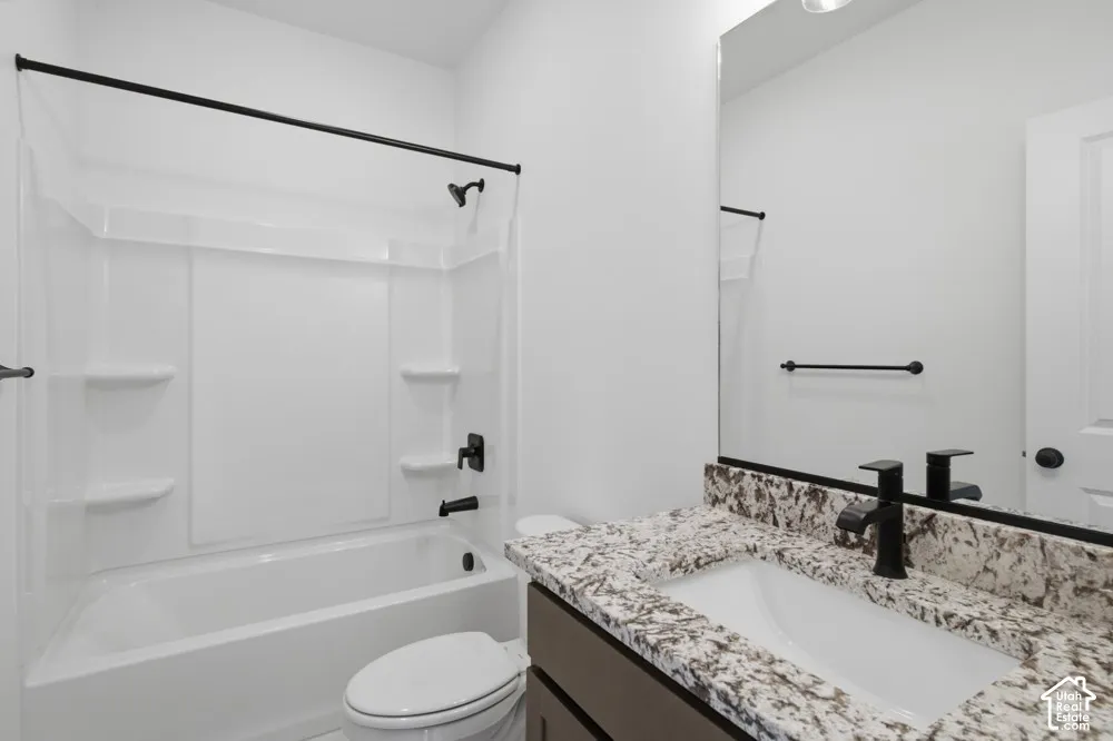 Bathroom featuring a vanity with stone-patterned countertop, under-mount sink, matte black faucet, full-width mirror, and a tub-shower combination with matte black hardware