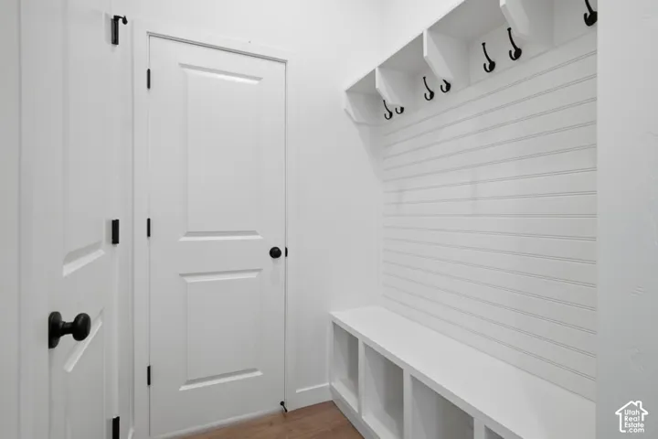 Built-in storage bench with lower cubbies, horizontal wall paneling, and upper shelving with integrated hooks featuring matte black hardware