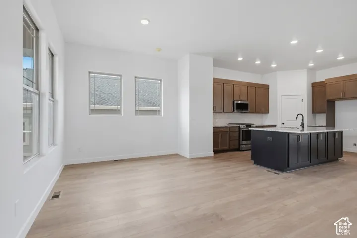 Kitchen featuring wood-finish flooring, a contrasting kitchen island with a stone countertop, recessed lighting, and wooden cabinetry