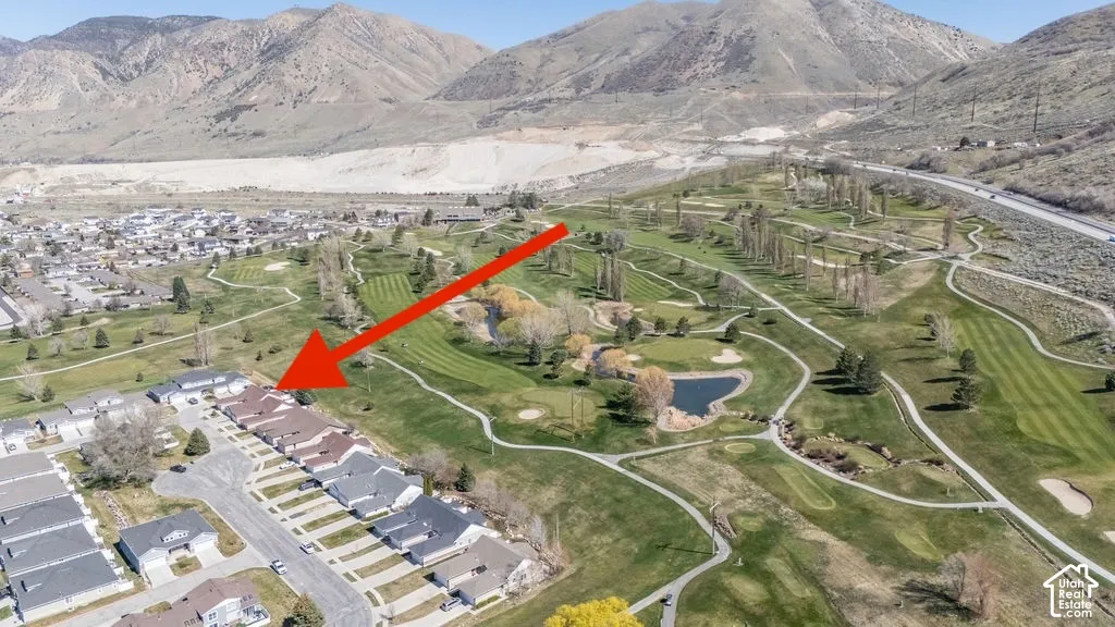 Aerial perspective featuring single-level residential architecture with asphalt shingle roofing, situated against a backdrop of mountainous terrain and expansive golf course grounds
