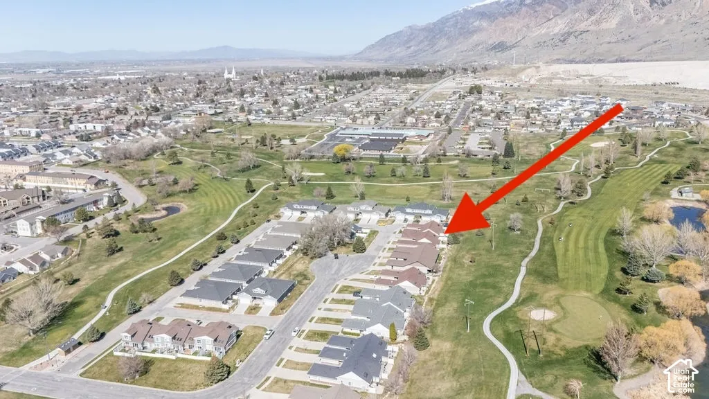 Aerial perspective of residential property featuring a multi-unit building with shingle roofing, situated on a golf course lot with mountain surroundings