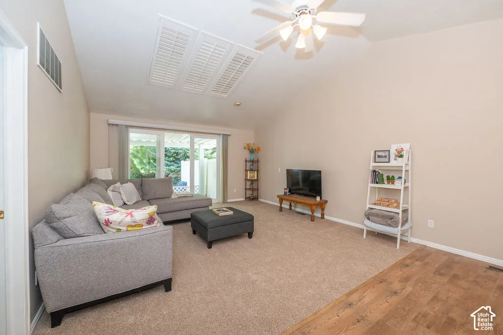 Vaulted ceiling with integrated ceiling fan, wood-finish flooring, neutral carpeting, and glass sliding door access to exterior space