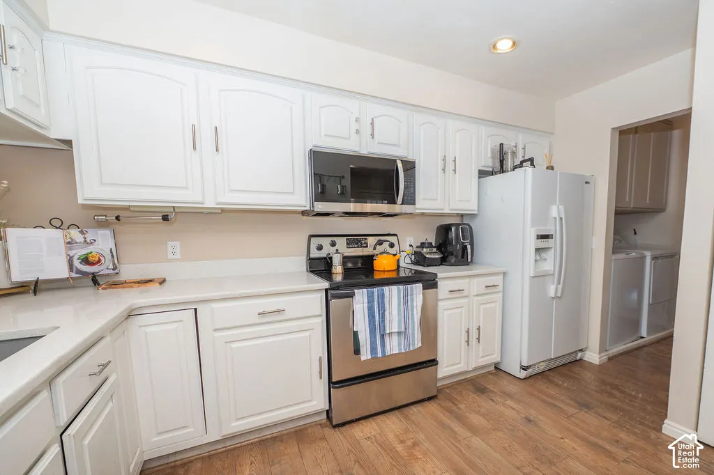 Kitchen featuring white cabinetry, solid-surface countertops, wood-finish flooring, and stainless steel appliances