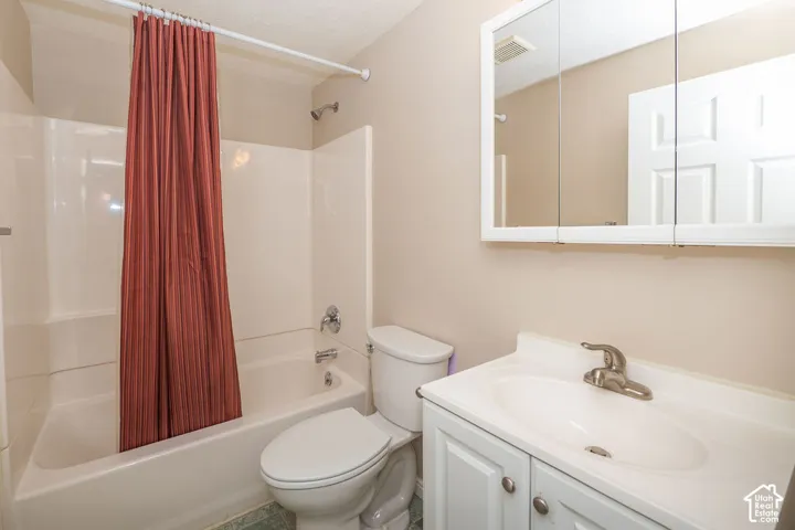 Bathroom featuring a white vanity cabinet with a integrated sink, brushed metal faucet, tri-fold medicine cabinet, and a shower-tub combination with a molded surround