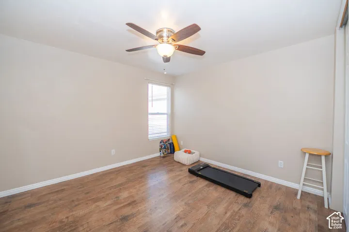 Room featuring wood-finish flooring, a neutral wall palette, a ceiling fan with integrated lighting, and a single window