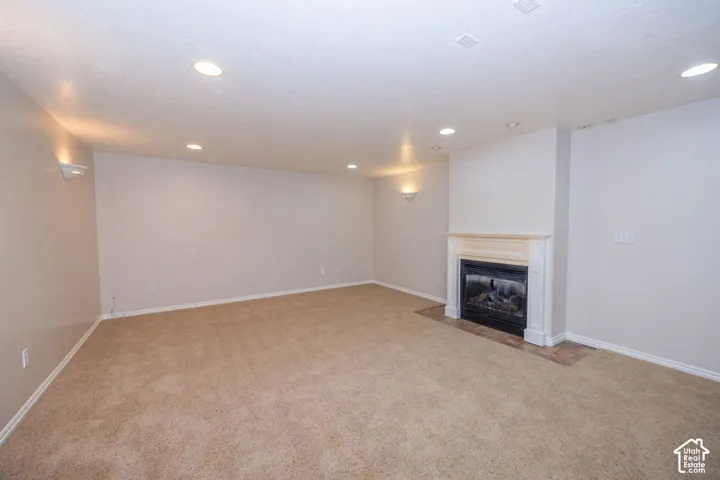 Fireplace with a classic white mantel, tile hearth, wall-mounted light fixtures, recessed ceiling lighting, and carpeted flooring