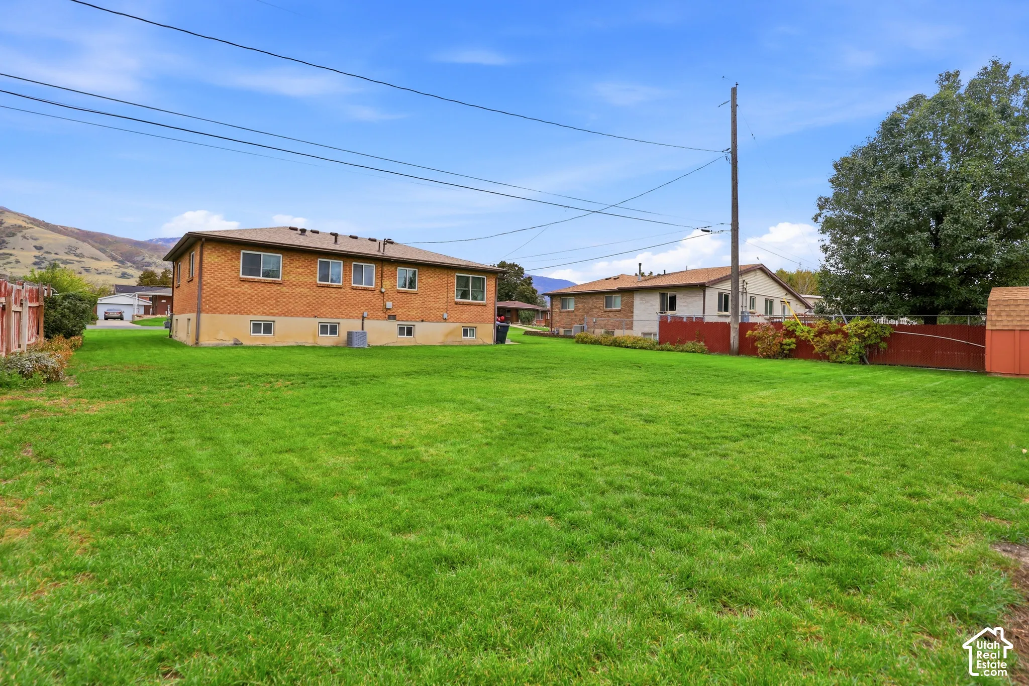 Expansive backyard featuring a large grass lawn, brick exterior siding, and perimeter fencing