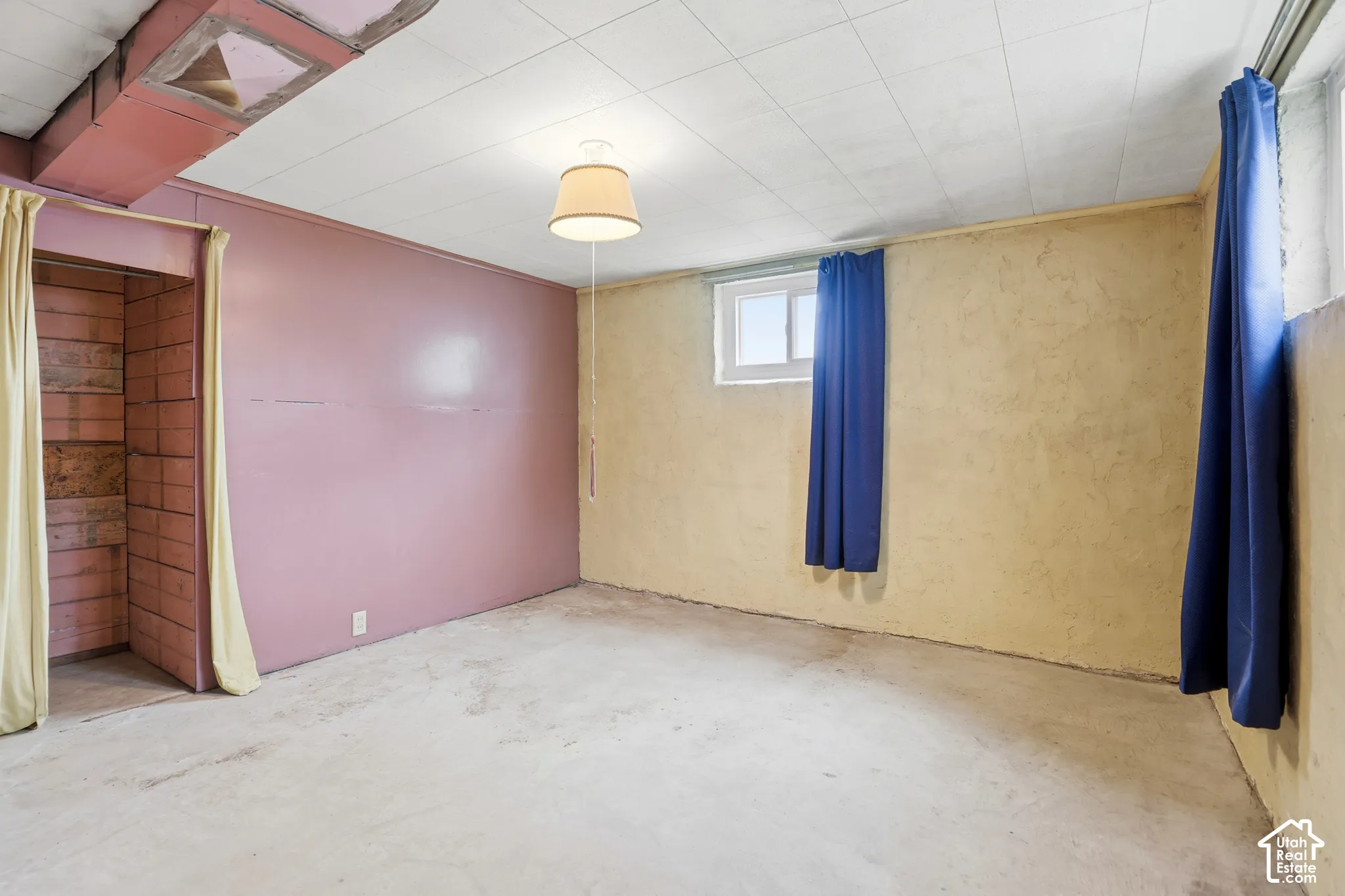 Finished space featuring painted walls, a drop ceiling, concrete flooring, and a sliding window