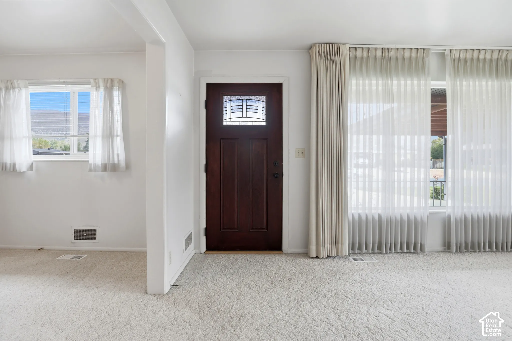 Entry featuring a solid wood door with decorative glass inlay, expansive windows, and wall-to-wall carpeting