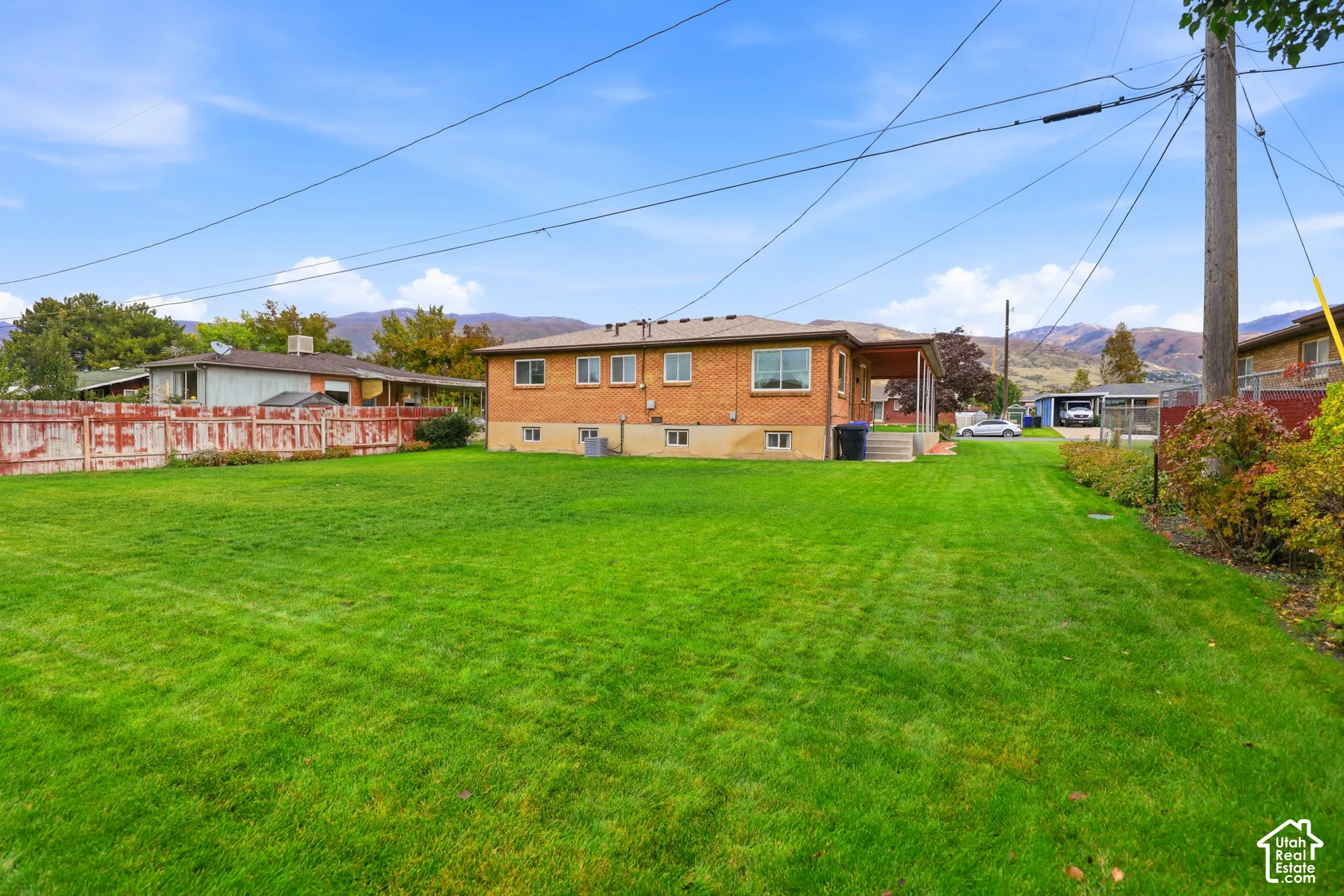 Expansive rear lawn featuring brick exterior siding, a covered patio area, and mountain scenery