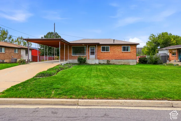 Single-level brick exterior featuring a covered carport, concrete driveway, and front lawn