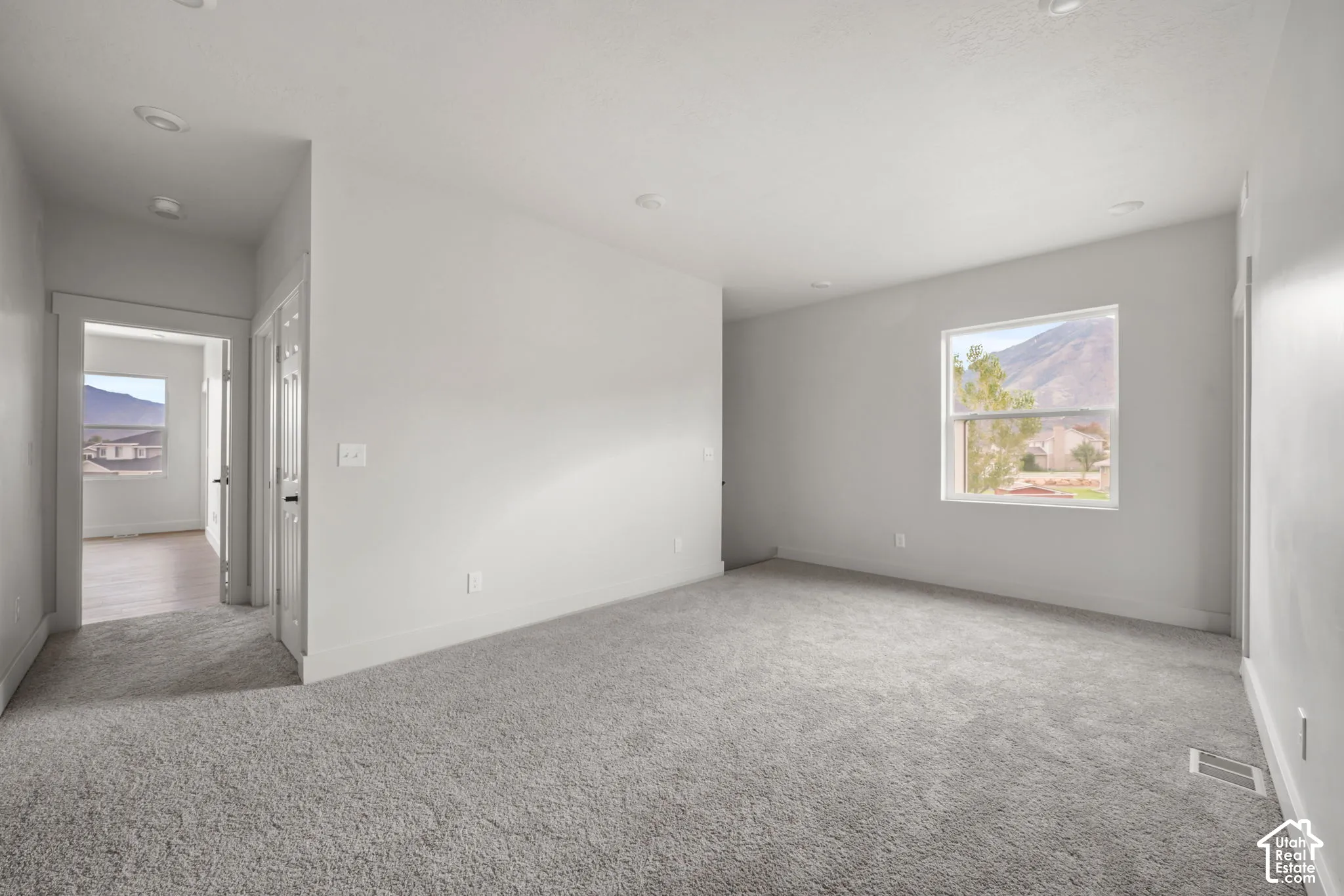 Neutral-toned interior space featuring recessed lighting, wall-to-wall carpeting, and double-pane windows with mountain scenery